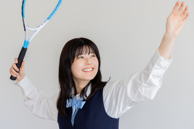 部活動でテニスをする女子高生